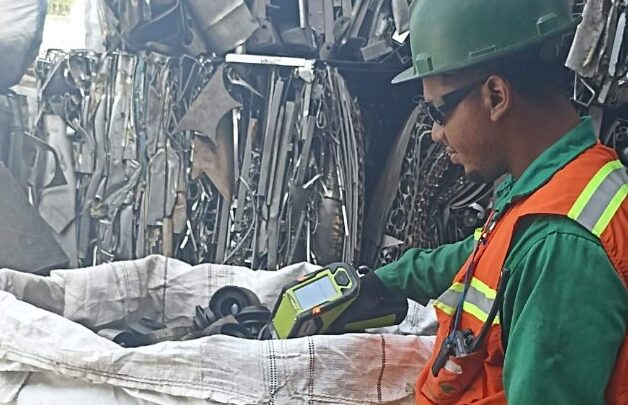 Worker analyzing metal with a handheld spectrometer